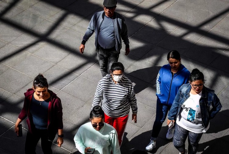 A Tourist Wearing A Face Mask Walks With Others As